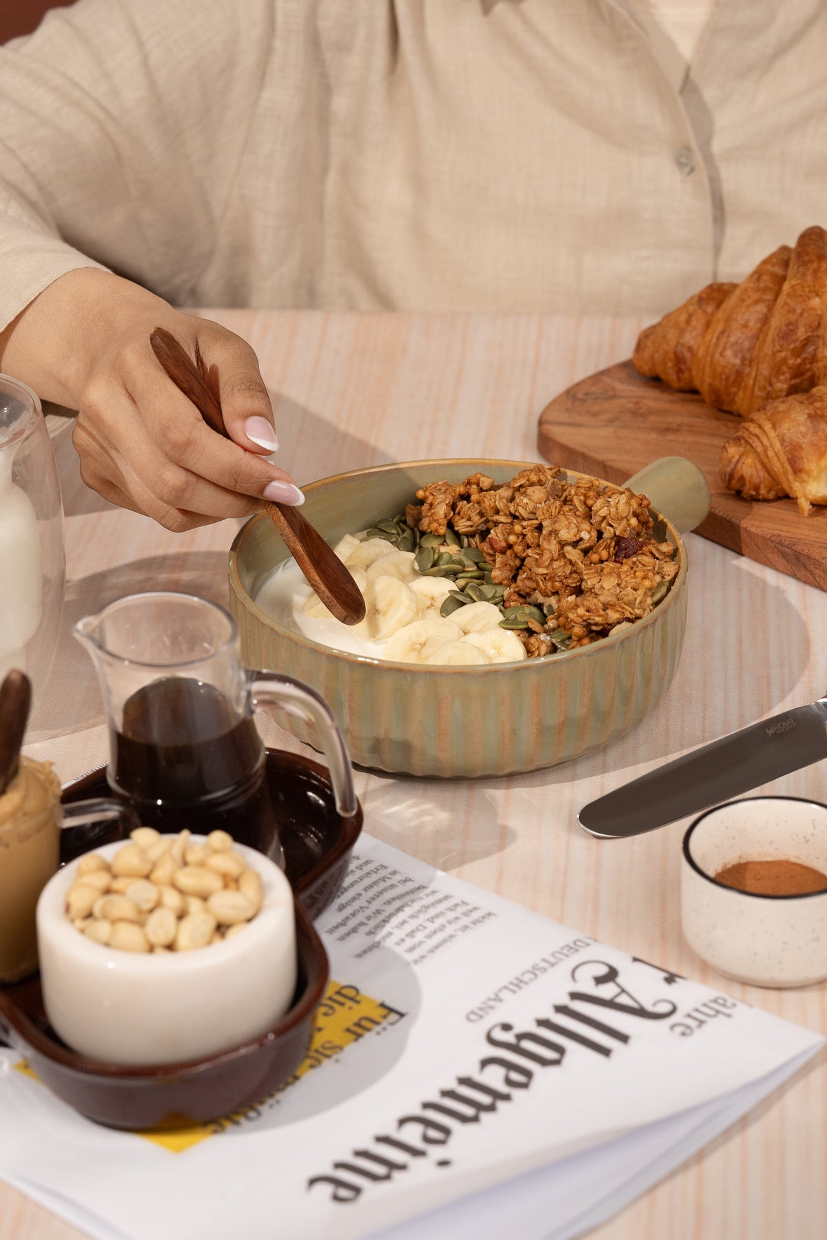 Peanut sync granola being spooned into a bowl of yogurt with muesli toppings